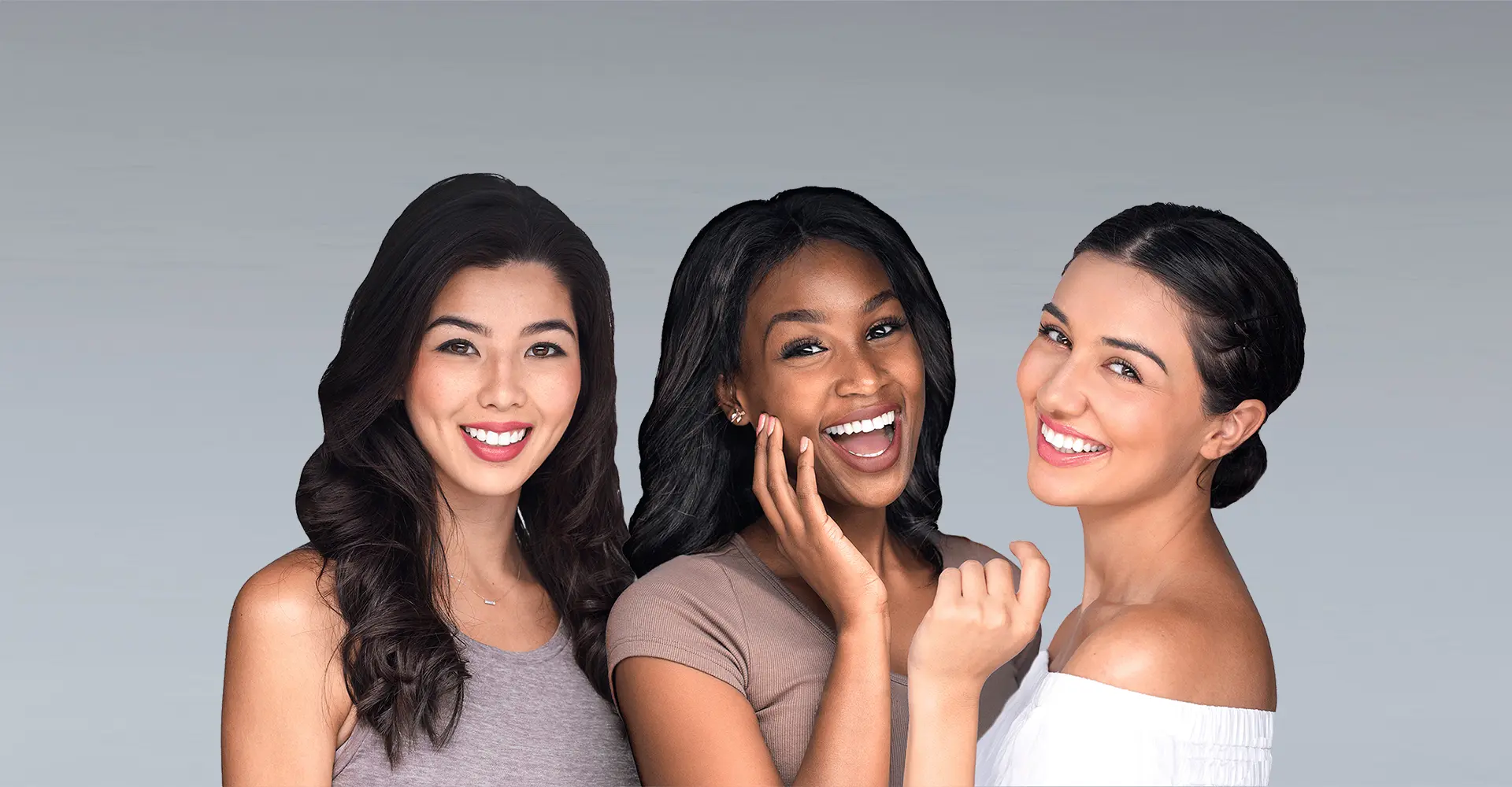 three women stand together smiling against a light gray background the woman on the left has long dark wavy hair and is wearing a light purple sleeveless top the middle woman has shoulder length dark hair and is wearing a beige shirt while the right woman glowing after her skinpen treatment dons an off shoulder white top